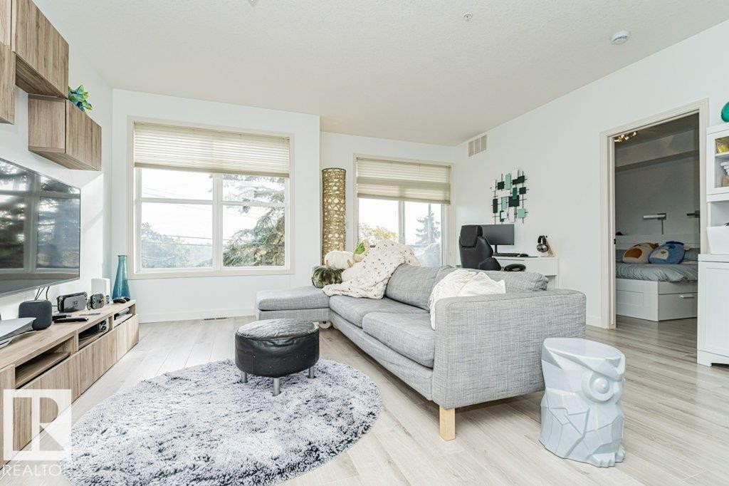 Light wood-finish flooring throughout, bright white walls, and built-in wood-finish media console - #202 9503 101 Av Nw, Edmonton, AB