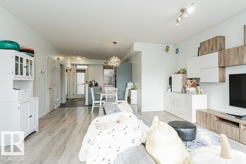 Open-concept living area with light wood-finish flooring, recessed lighting, and track lighting - #202 9503 101 Av Nw, Edmonton, AB
