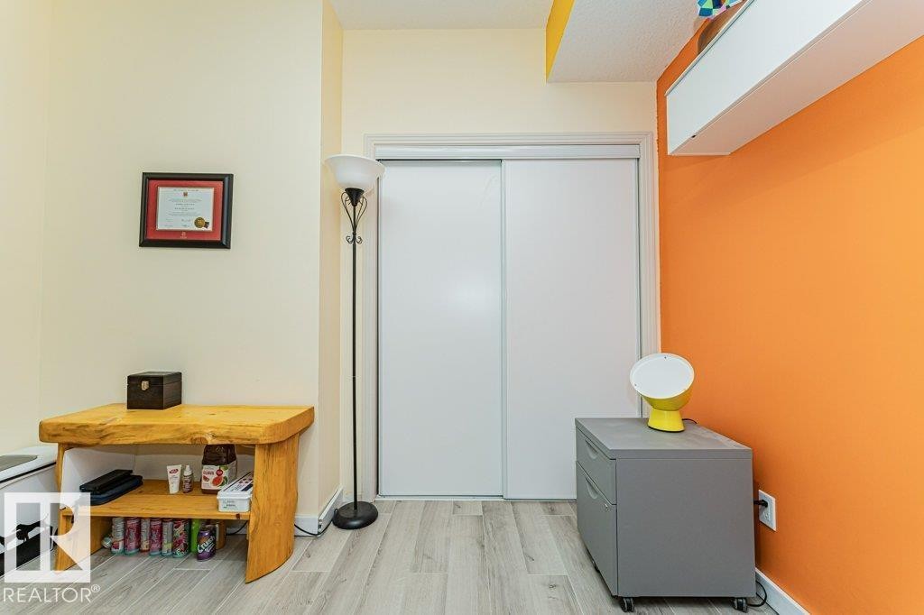 Light wood-finish flooring with white baseboards - #202 9503 101 Av Nw, Edmonton, AB