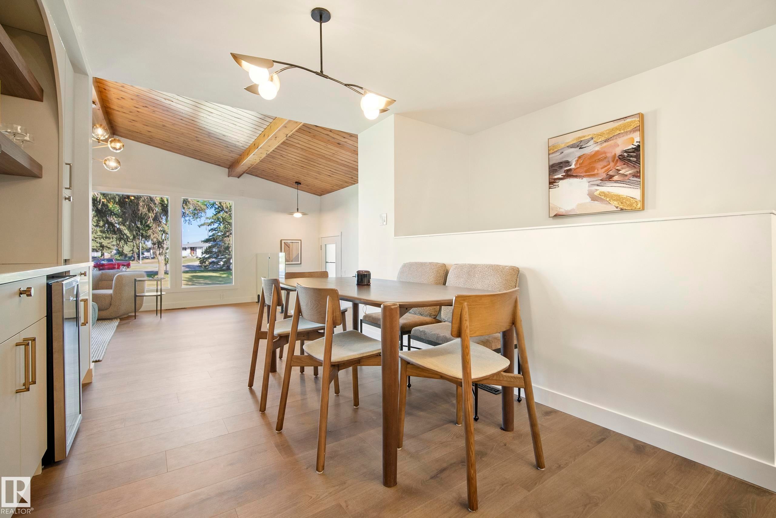 Vaulted wood-paneled ceiling with exposed beams, wood-finish flooring, built-in beverage refrigerator, and a contemporary light fixture - 10316 42 Street Nw, Edmonton, AB