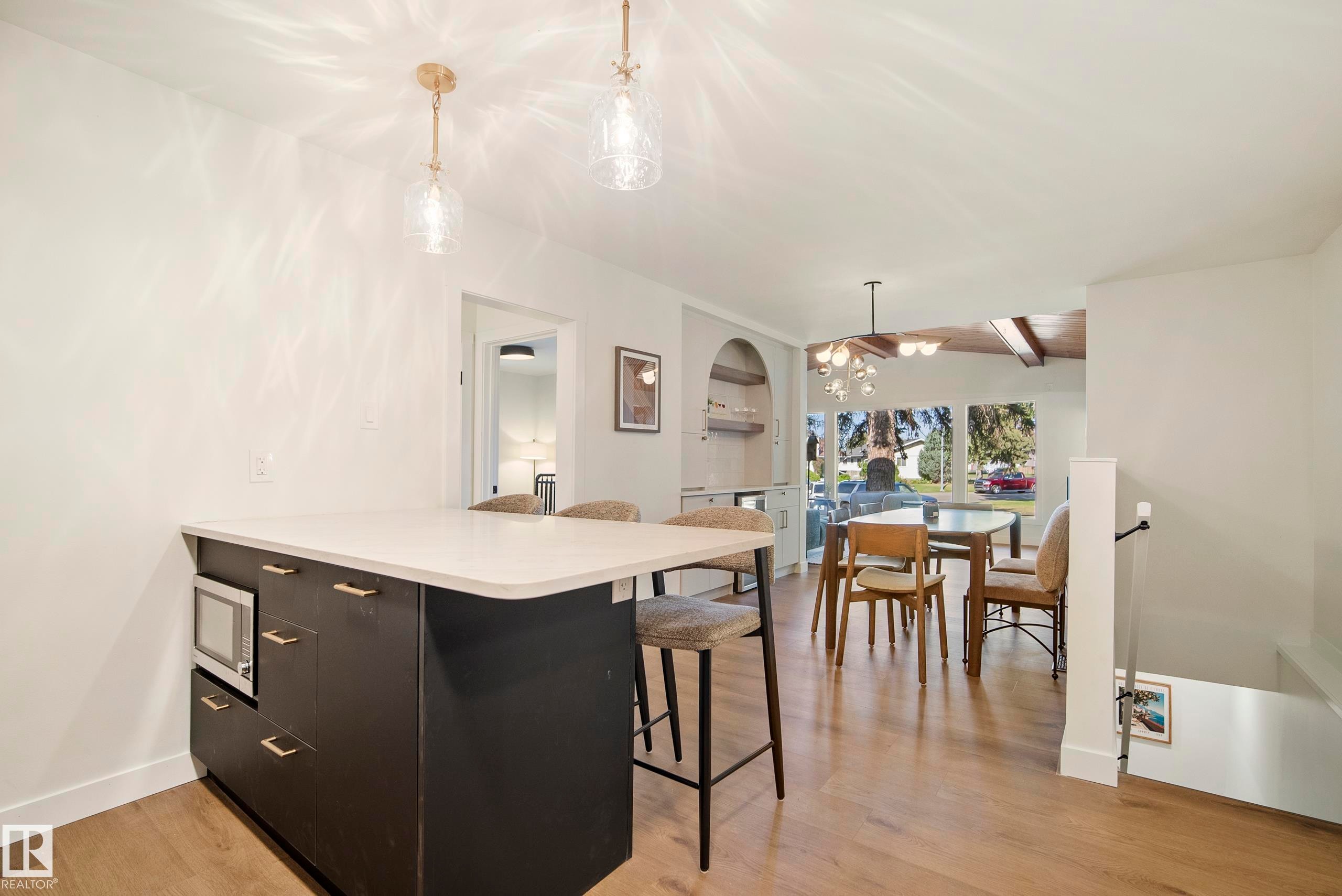 Kitchen island with a light-toned countertop, wood-finish flooring, recessed lighting, and a dining area with a ceiling fan - 10316 42 Street Nw, Edmonton, AB