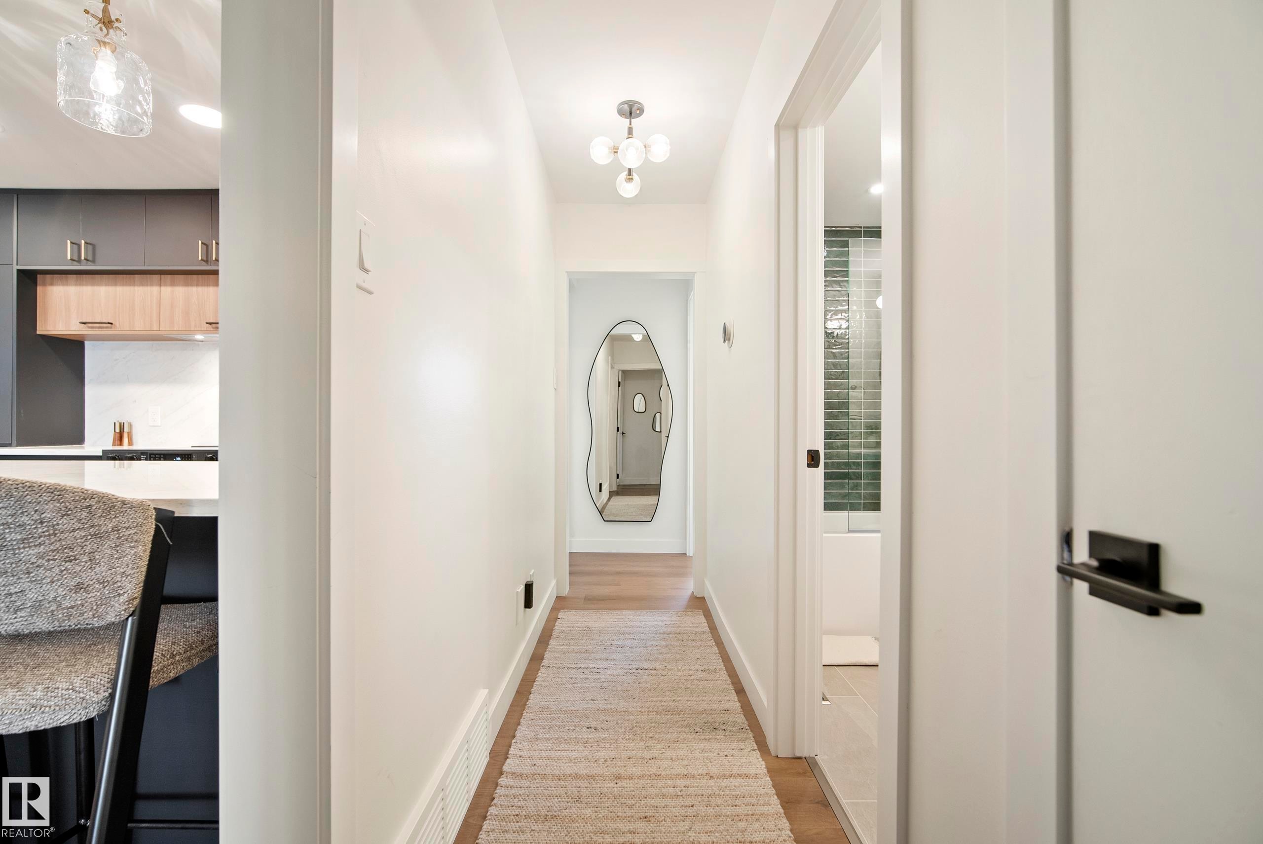 Hallway featuring wood-finish flooring, recessed lighting, and a modern light fixture - 10316 42 Street Nw, Edmonton, AB