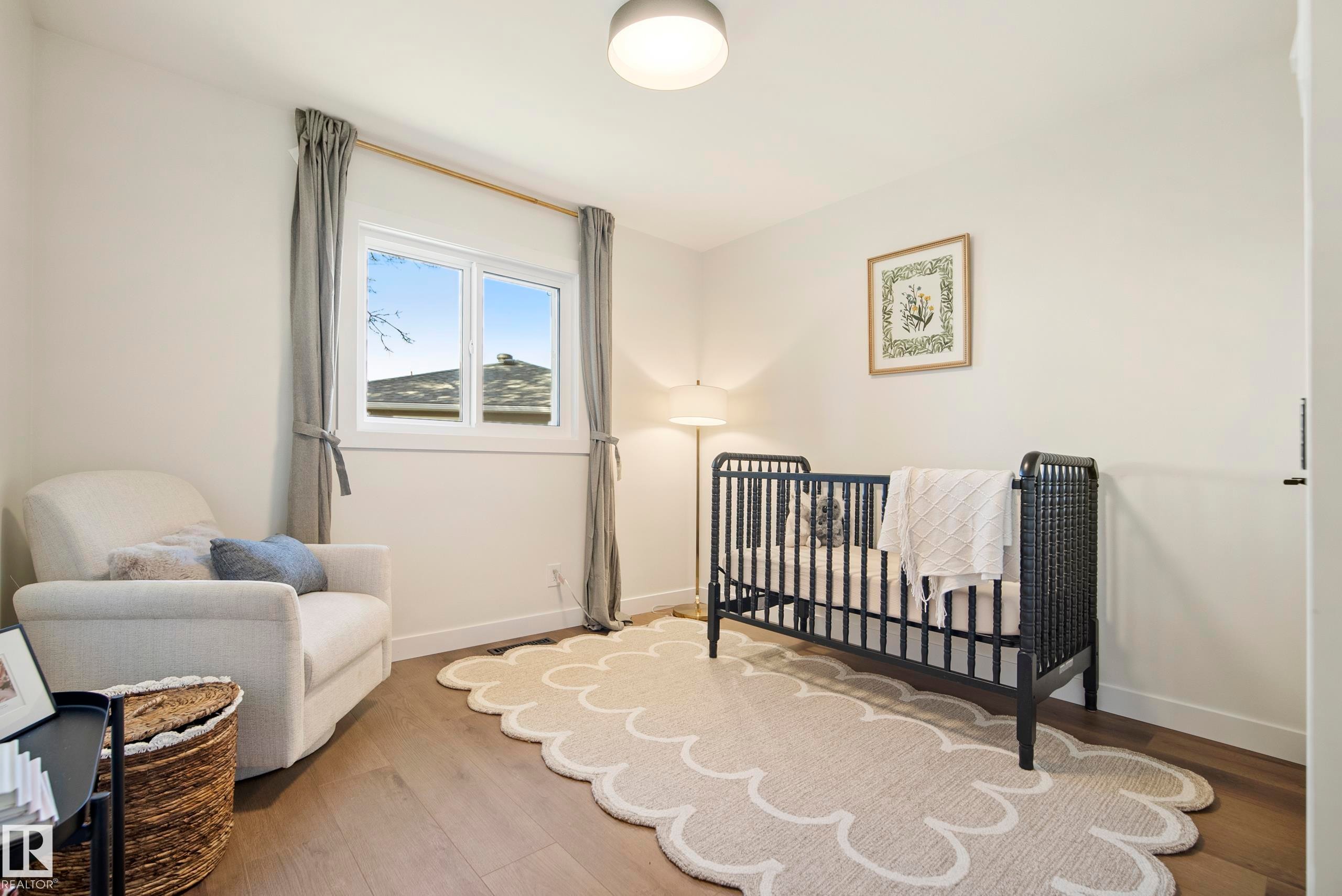 Light wood-finish flooring, a double-pane window with neutral drapes, and a flush-mount ceiling light fixture - 10316 42 Street Nw, Edmonton, AB