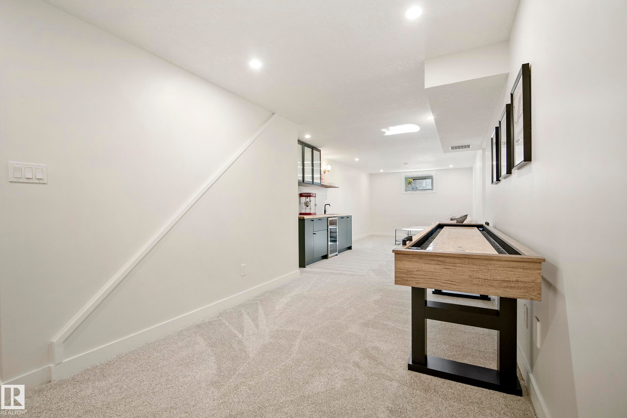 Spacious recreation room featuring recessed lighting, light-toned carpeting, and a built-in wet bar with dark cabinetry - 10316 42 Street Nw, Edmonton, AB