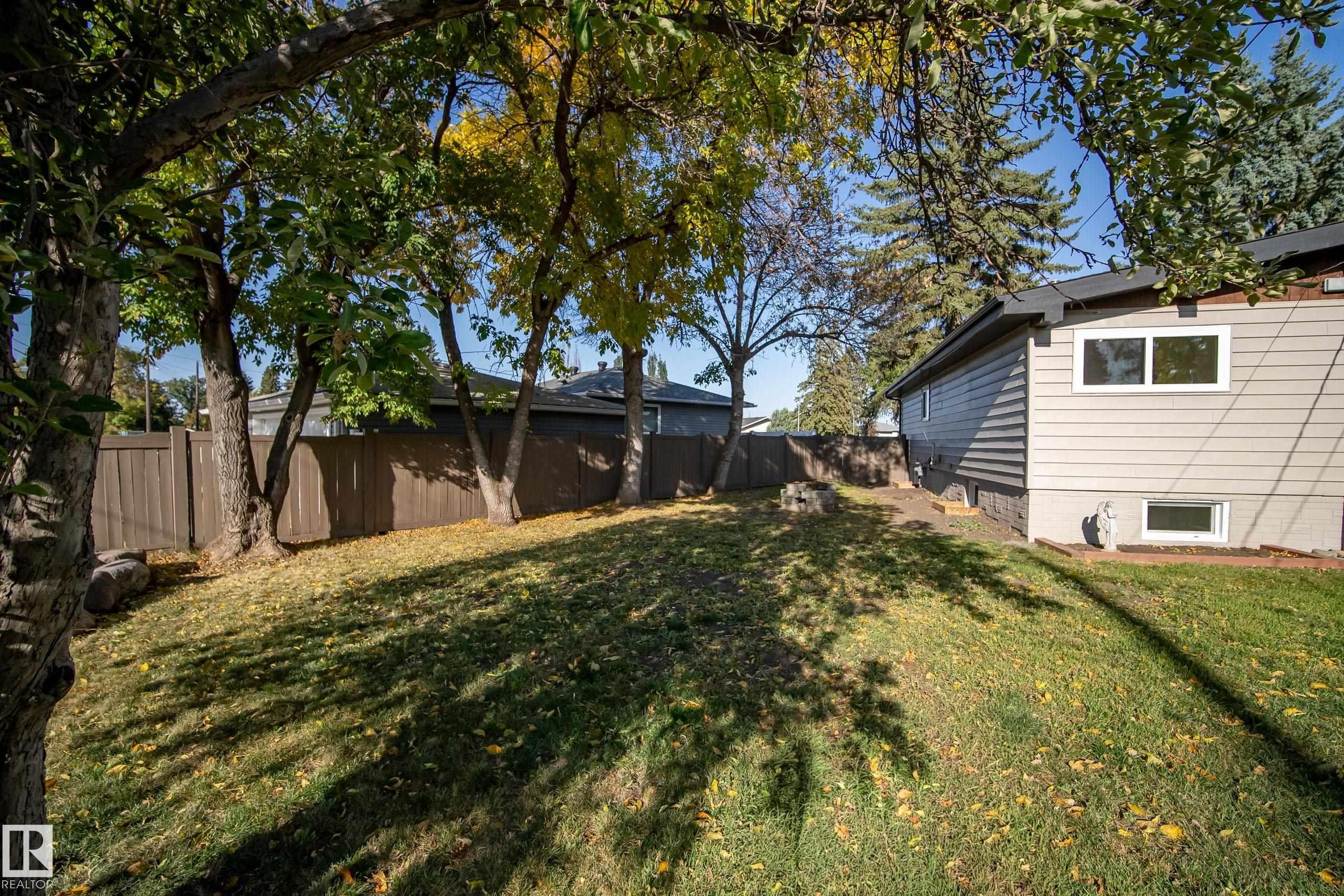 Expansive backyard featuring mature trees, a manicured lawn, and a privacy fence - 10316 42 Street Nw, Edmonton, AB