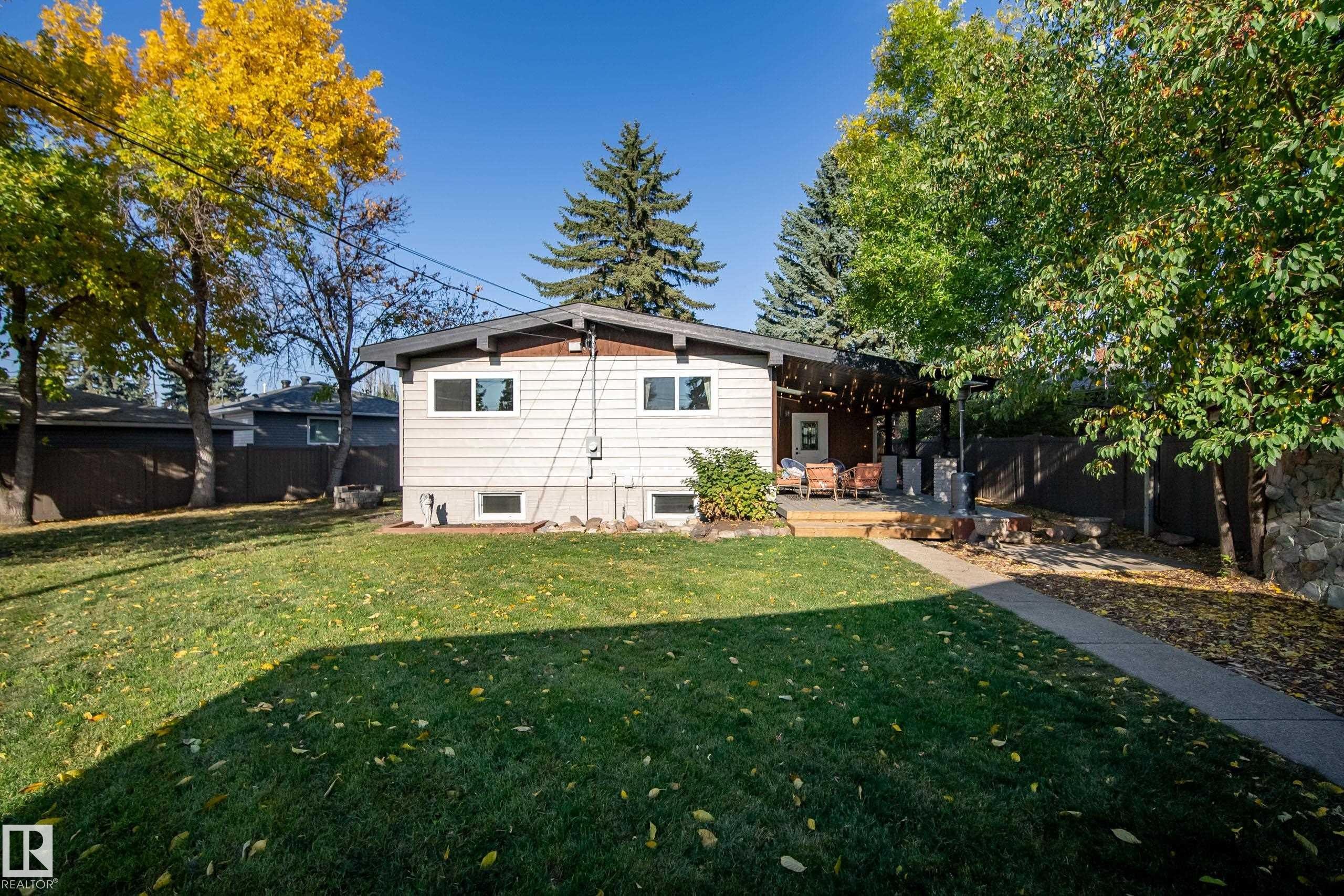 Expansive lawn with mature trees and a paved walkway leading to a wooden deck - 10316 42 Street Nw, Edmonton, AB