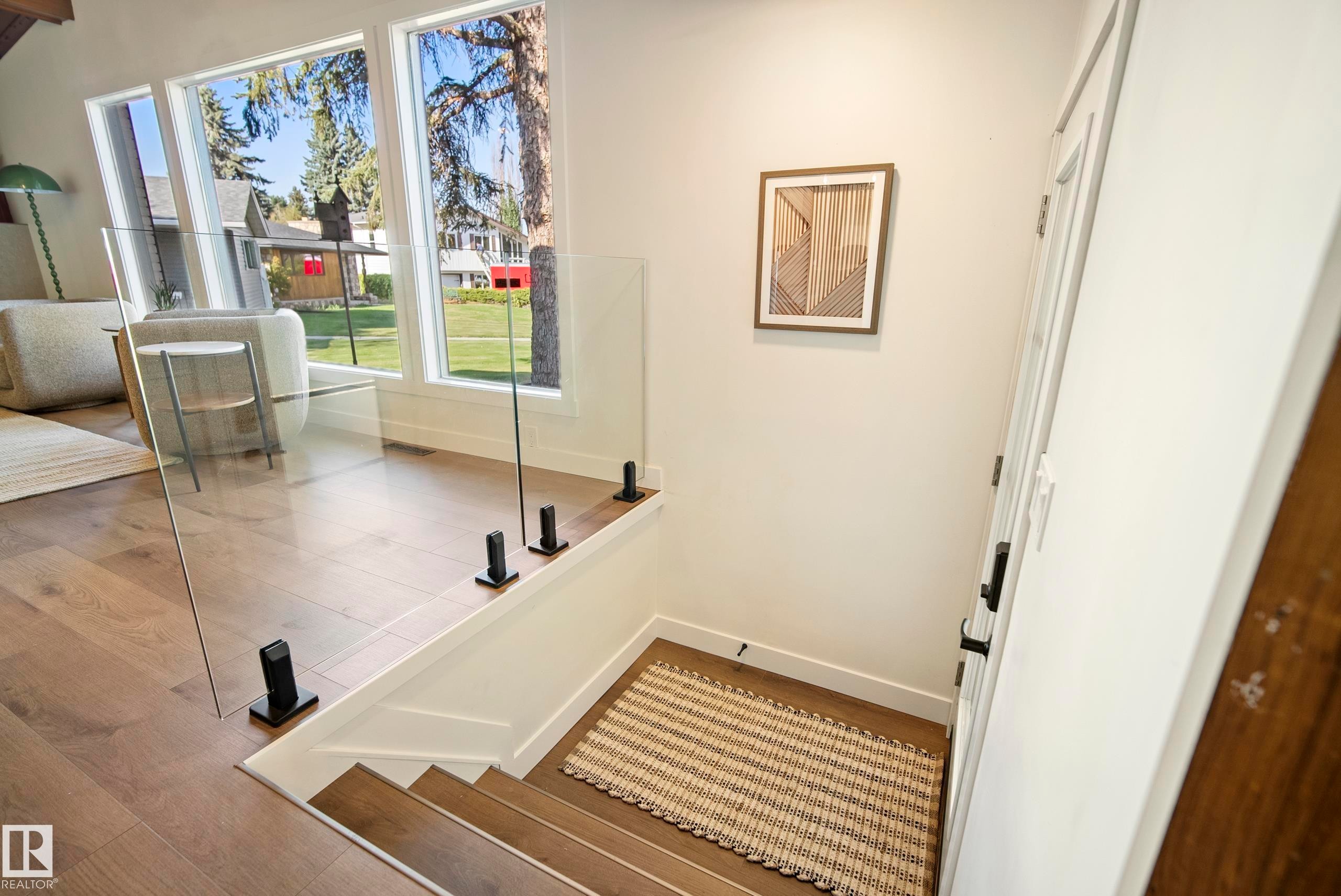 Hardwood flooring throughout, featuring a glass panel railing system with black hardware - 10316 42 Street Nw, Edmonton, AB