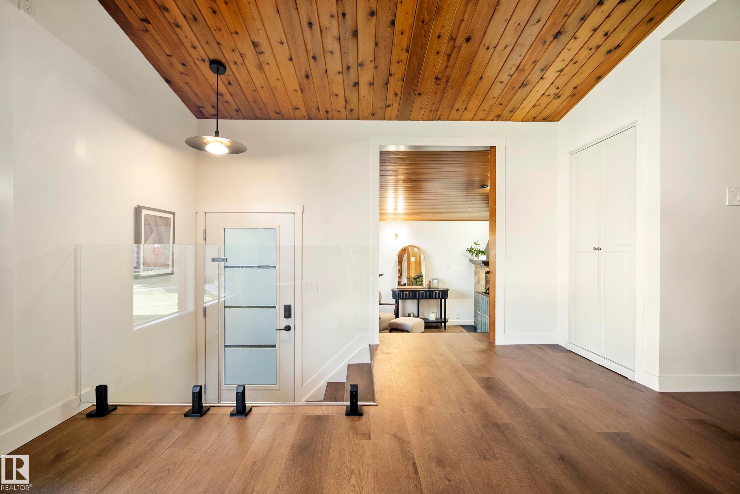 Wood-finish flooring, wood plank ceiling, white walls, built-in closet, and a glass panel railing - 10316 42 Street Nw, Edmonton, AB