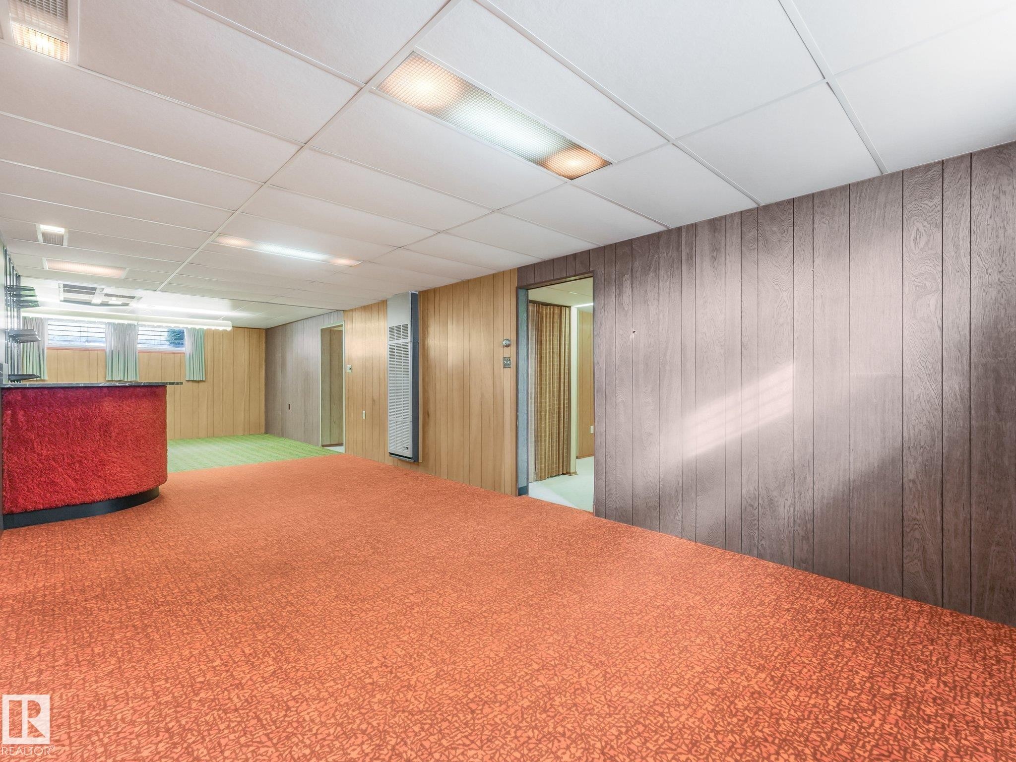 Expansive room featuring orange patterned carpeting and wood-paneled walls - 5904 94 Avenue Nw, Edmonton, AB