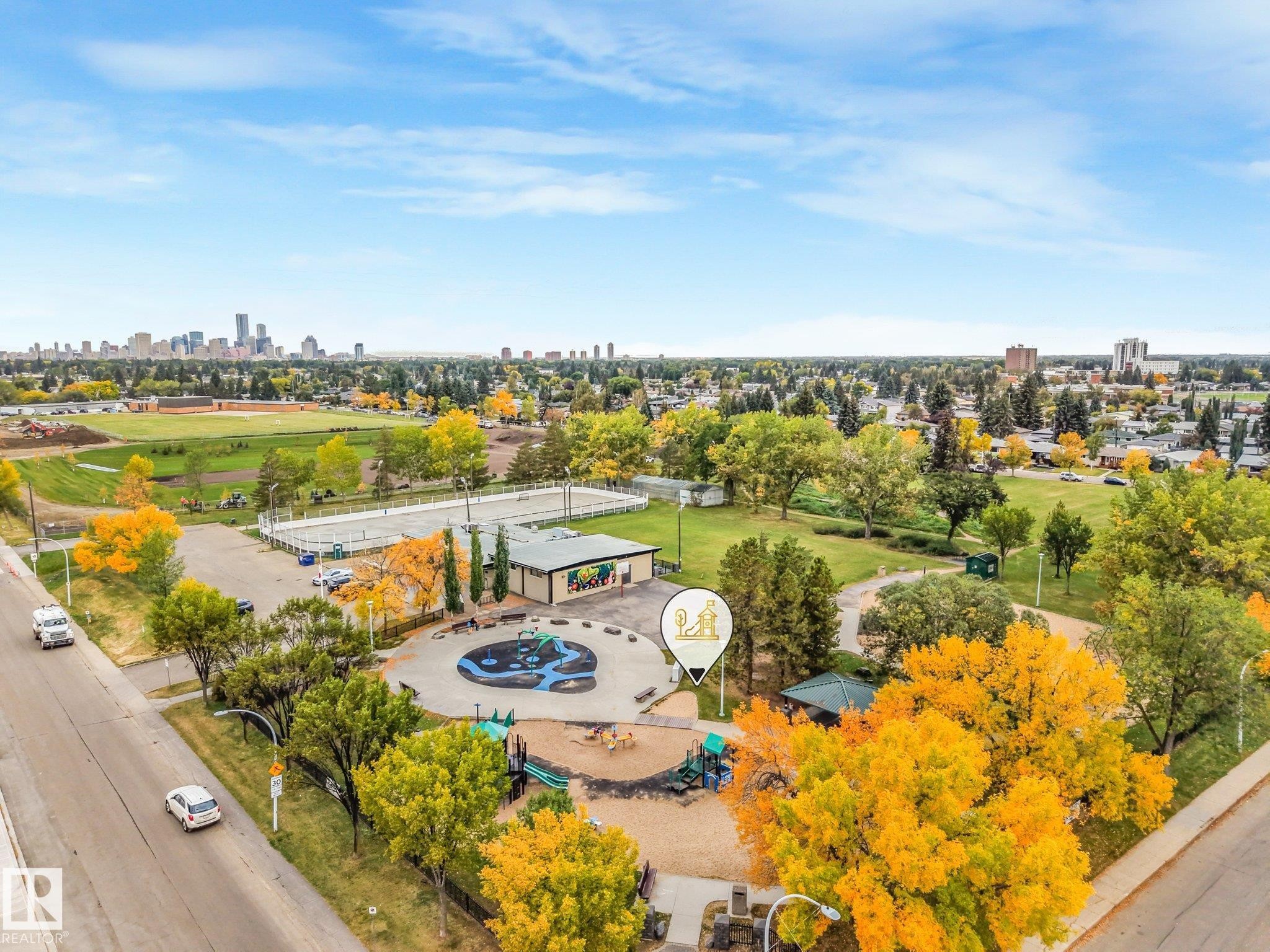 City skyline visible in the distance, expansive green spaces, sports courts, and a playground area - 5904 94 Avenue Nw, Edmonton, AB