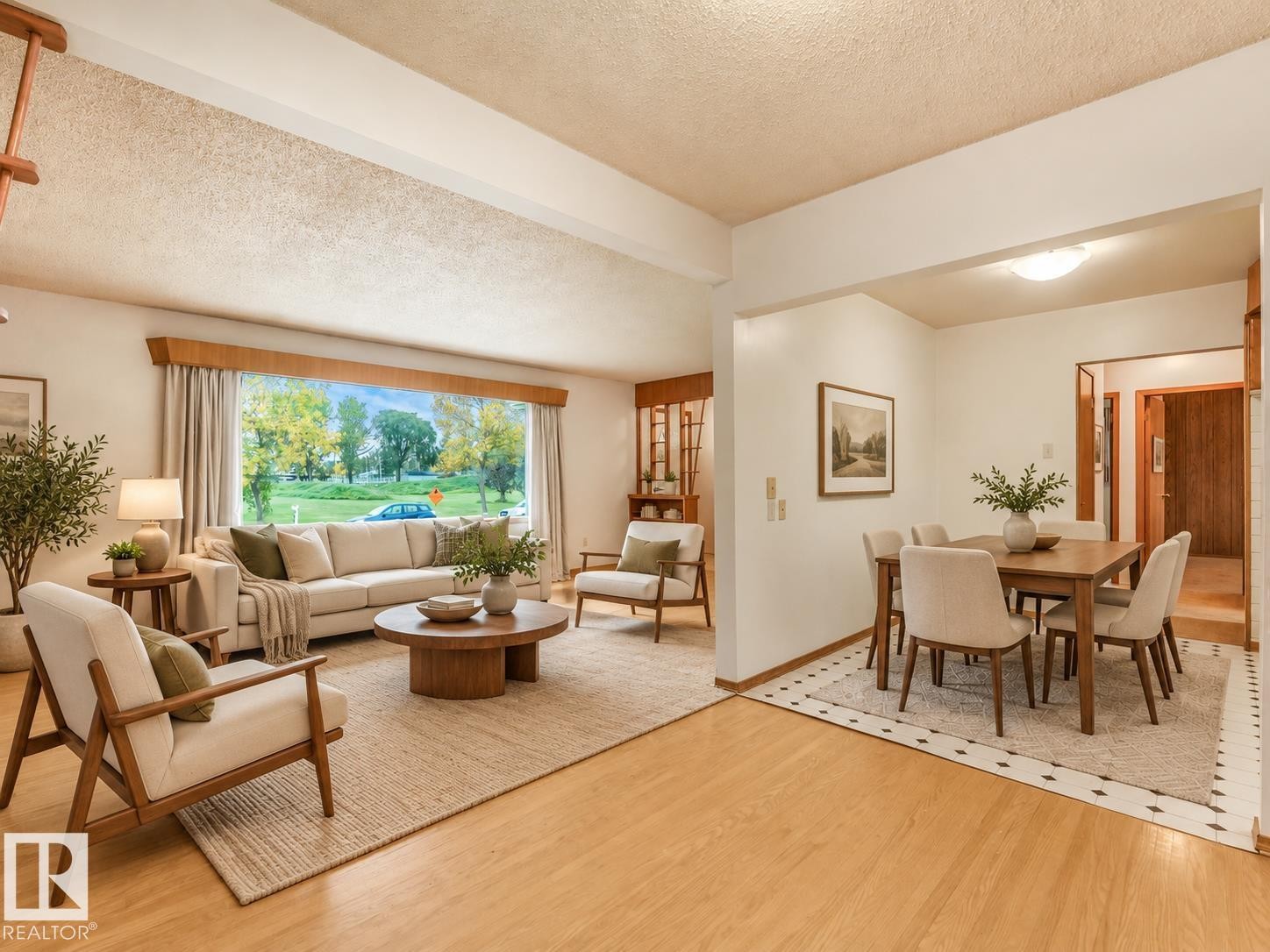 Spacious living area featuring a large picture window, wood-finish flooring, and an open dining area with a tiled accent border - 5904 94 Avenue Nw, Edmonton, AB