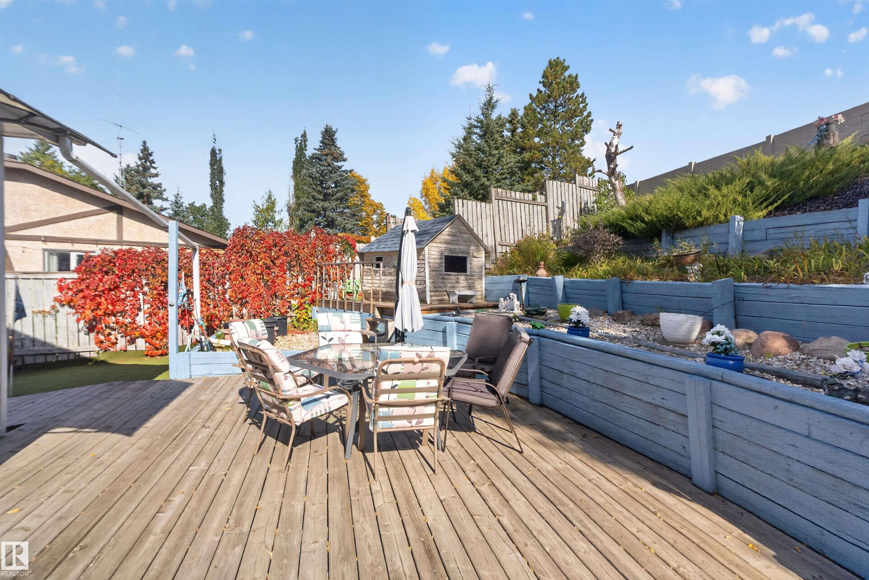 Expansive wood deck with tiered wood planters featuring established shrubbery, surrounded by mature trees - 1519 104 Street Nw, Edmonton, AB