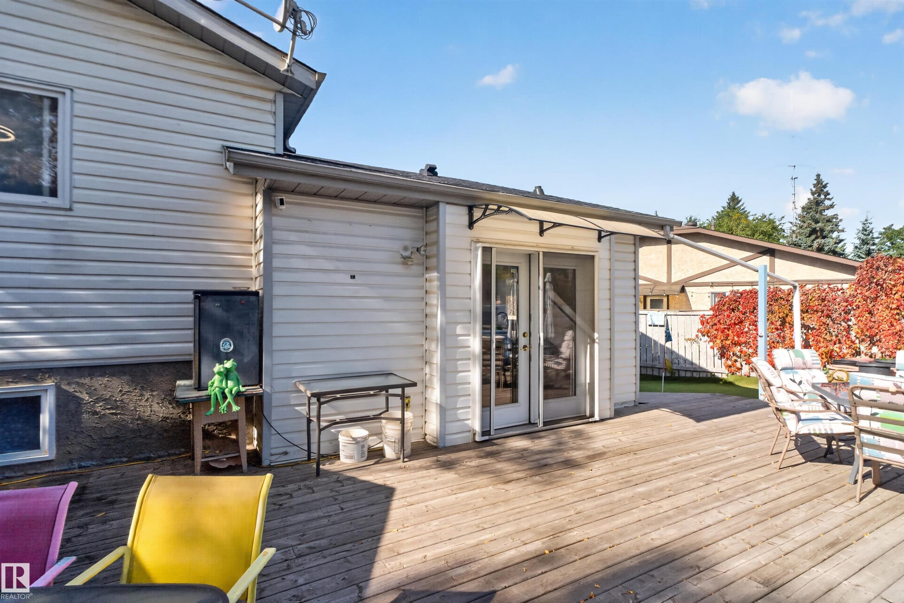 Expansive wood-finish deck with white vinyl siding exterior and multi-panel glass doors - 1519 104 Street Nw, Edmonton, AB