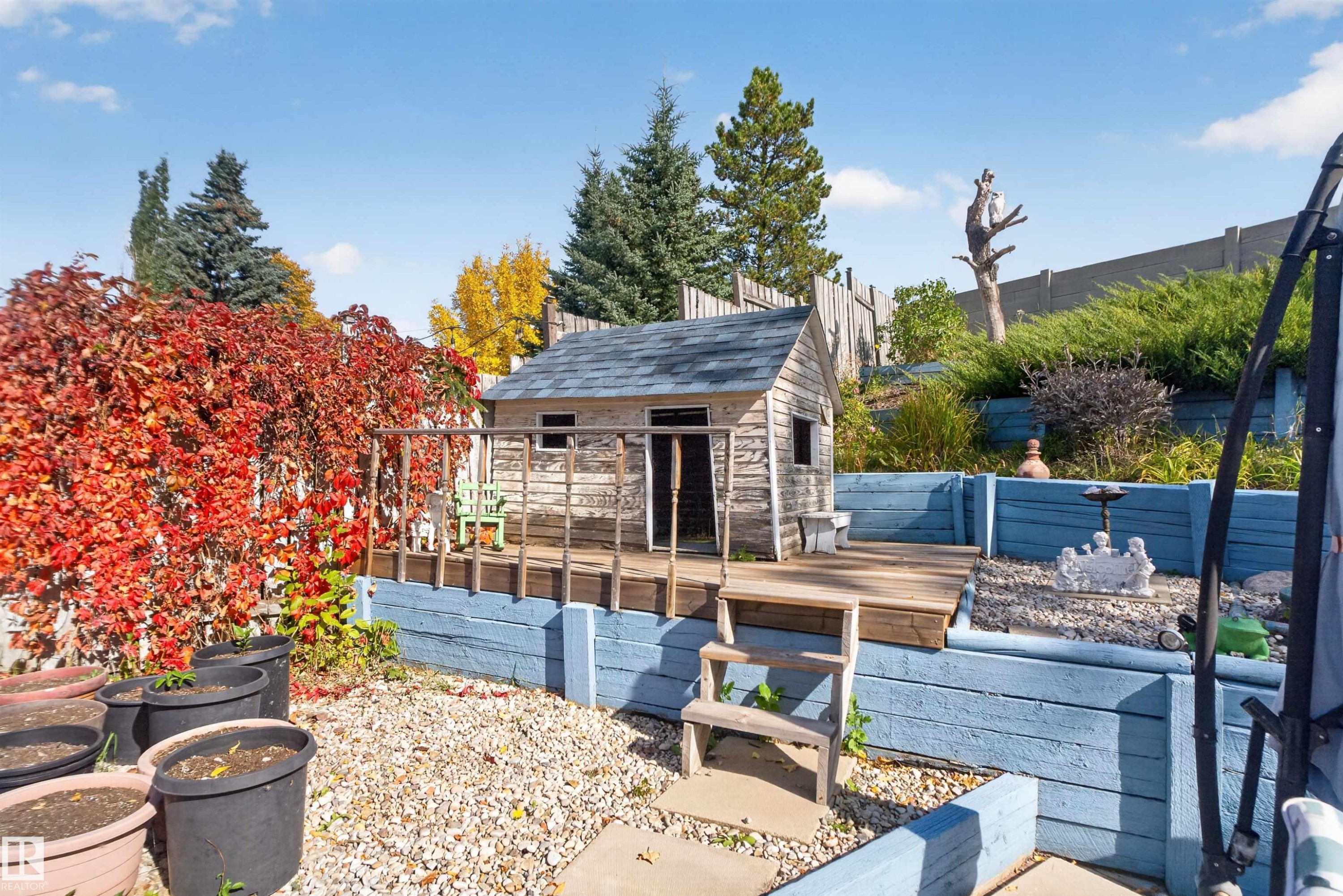 Tiered backyard featuring a wooden playhouse, wood decking, and a gravel ground cover - 1519 104 Street Nw, Edmonton, AB