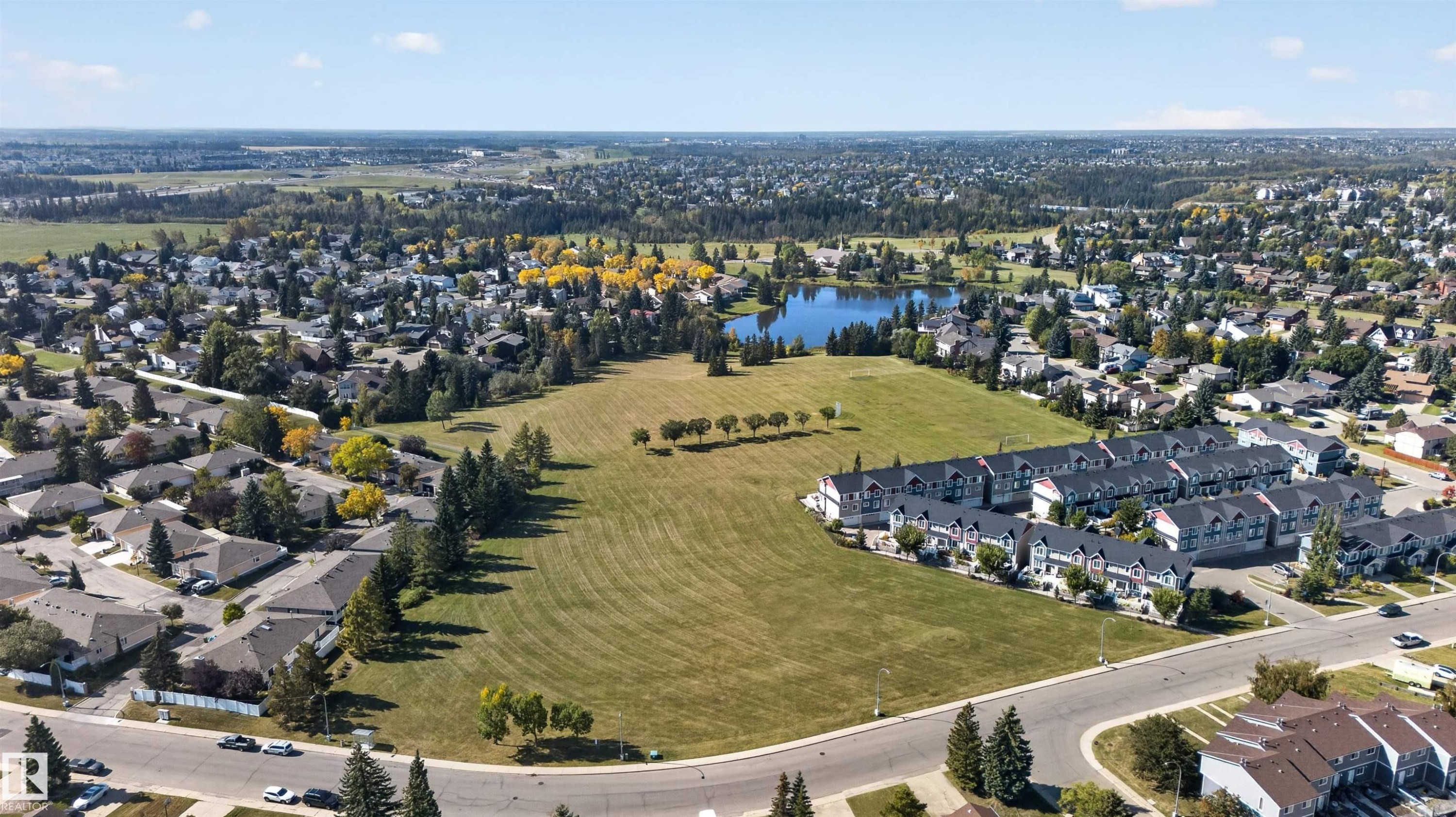 Expansive open field with surrounding residential properties, mature trees, and a lake - 1519 104 Street Nw, Edmonton, AB