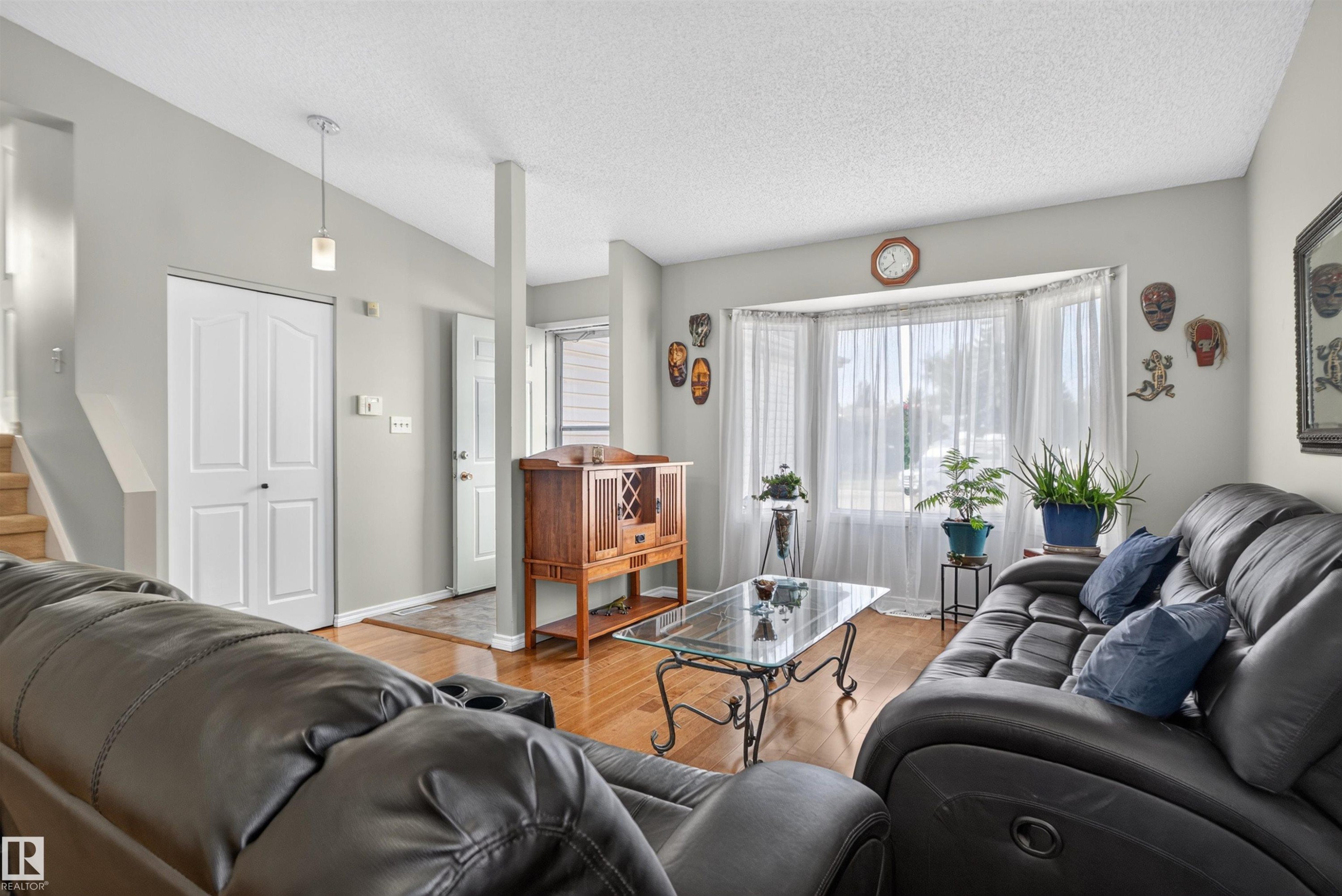 Recessed bay window, wood-finish flooring, light grey wall paint, white trim, and a contemporary pendant light fixture - 1519 104 Street Nw, Edmonton, AB