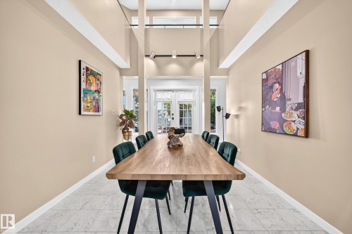 Two-story ceiling, light-toned walls, tiled flooring, track lighting, and French doors - 5830 181 Street Nw, Edmonton, AB 