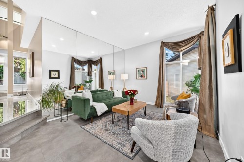 Recessed lighting illuminates the living area with tile flooring and a mirrored accent wall - 5830 181 Street Nw, Edmonton, AB 