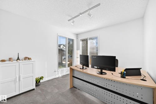 Recessed track lighting illuminates the space featuring large windows and sliding glass doors - 5830 181 Street Nw, Edmonton, AB 