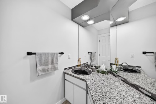 Dual vanity with speckled countertops, dark basin sinks, and integrated overhead lighting - 5830 181 Street Nw, Edmonton, AB 