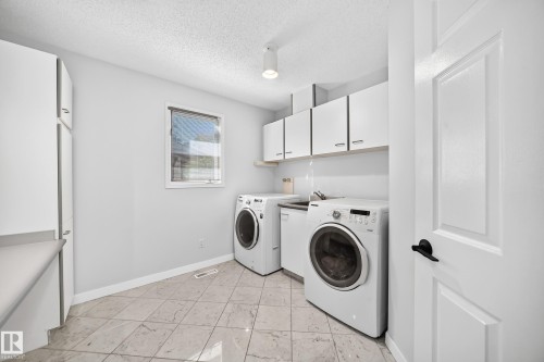 Tiled flooring with white cabinetry and a utility sink - 5830 181 Street Nw, Edmonton, AB 