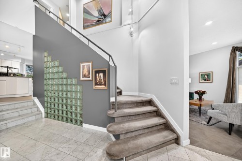 Two-story foyer with tile flooring, glass block wall feature, and carpeting on stairs - 5830 181 Street Nw, Edmonton, AB 