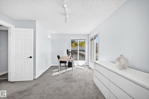 Light gray wall color, textured ceiling, six-panel interior door with matte black hardware, dual windows with white trim, and track lighting - 5830 181 Street Nw, Edmonton, AB 