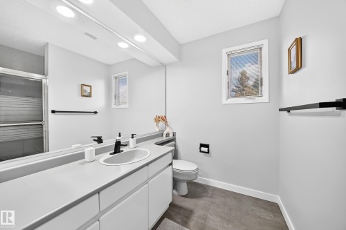 Full-width vanity with an integrated sink, black-finish faucet, and substantial mirror - 5830 181 Street Nw, Edmonton, AB 