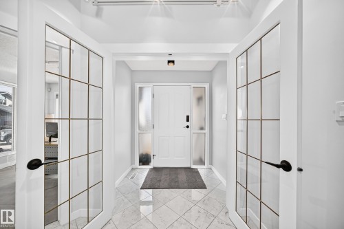 Foyer featuring patterned tile flooring and a solid panel entry door with frosted glass sidelights - 5830 181 Street Nw, Edmonton, AB 