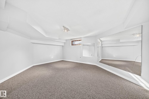 Recessed ceiling, neutral carpeting, track lighting, built-in wall mirrors, and a window - 5830 181 Street Nw, Edmonton, AB 