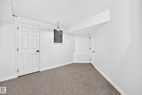 Recessed window opening, neutral color palette, paneled interior doors, textured ceiling, and a ceiling-mounted light fixture - 5830 181 Street Nw, Edmonton, AB 