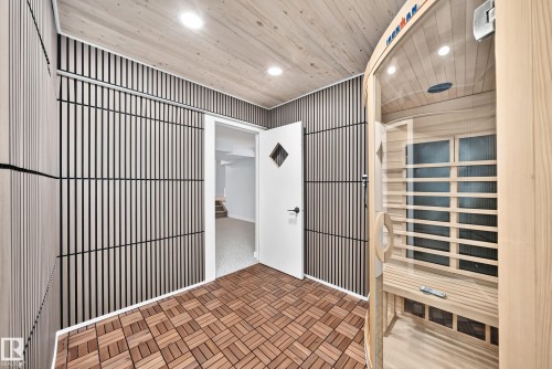 Infrared sauna with a glass door, wood-finish slatted walls, wood-finish plank ceiling, and wood-finish tile flooring - 5830 181 Street Nw, Edmonton, AB 