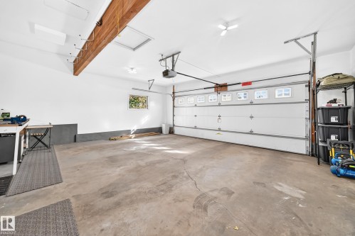 Spacious garage with exposed wooden beam, white walls, and concrete flooring - 5830 181 Street Nw, Edmonton, AB 