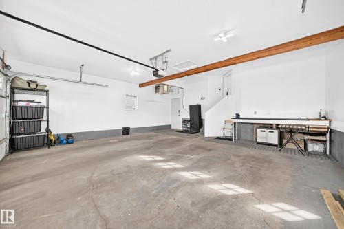 Spacious garage with exposed wood beam, overhead lighting, and built-in workbench - 5830 181 Street Nw, Edmonton, AB 