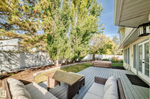 Expansive backyard featuring a large deck, mature trees, a manicured lawn, and a privacy fence - 5830 181 Street Nw, Edmonton, AB 