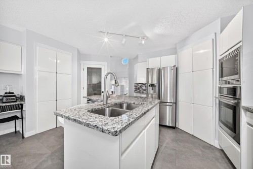 Kitchen island with dual stainless steel sinks and a chrome gooseneck faucet - 5830 181 Street Nw, Edmonton, AB 