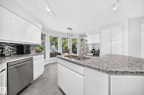 White cabinetry, granite countertops, stainless steel dishwasher, tile flooring, and a mosaic tile backsplash - 5830 181 Street Nw, Edmonton, AB 