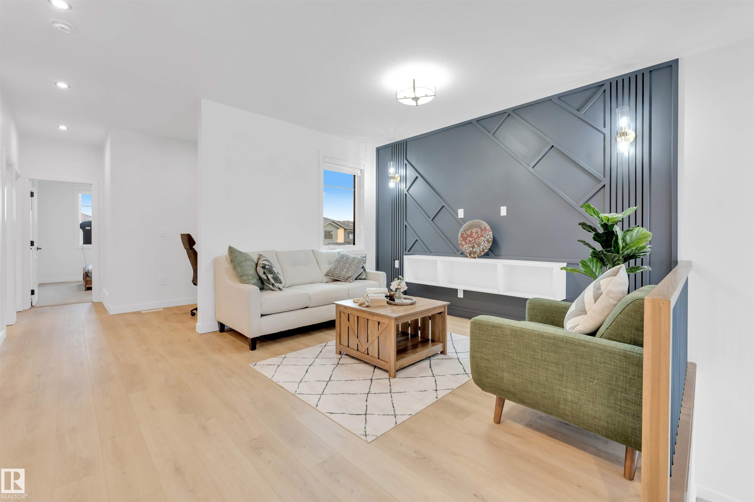 Wood-finish flooring throughout, recessed ceiling lighting, a distinctive accent wall with geometric paneling, and a built-in shelving unit - 2 Tenuto Link, Spruce Grove, AB
