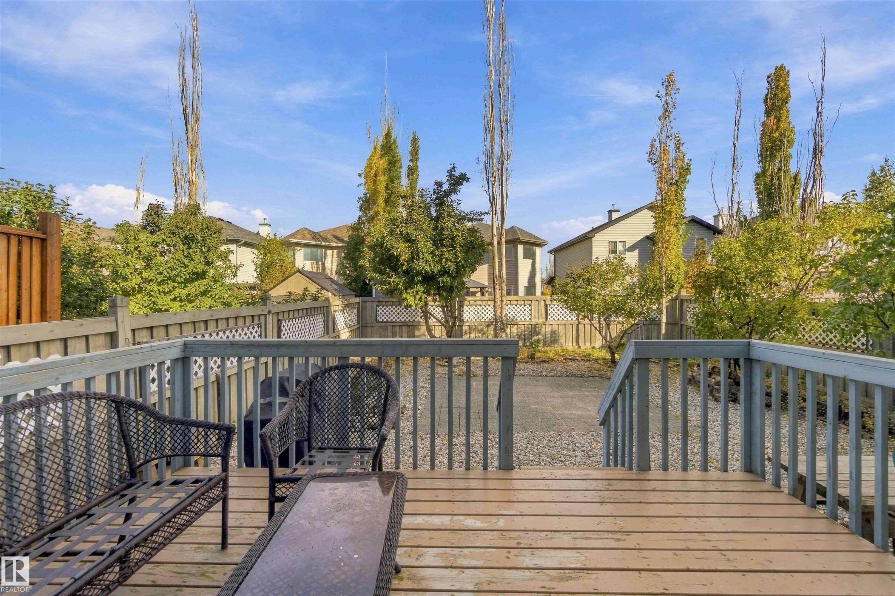 Spacious wood-finish deck with railings, providing access to a graveled yard area - 3524 Mclean Crescent Sw, Edmonton, AB