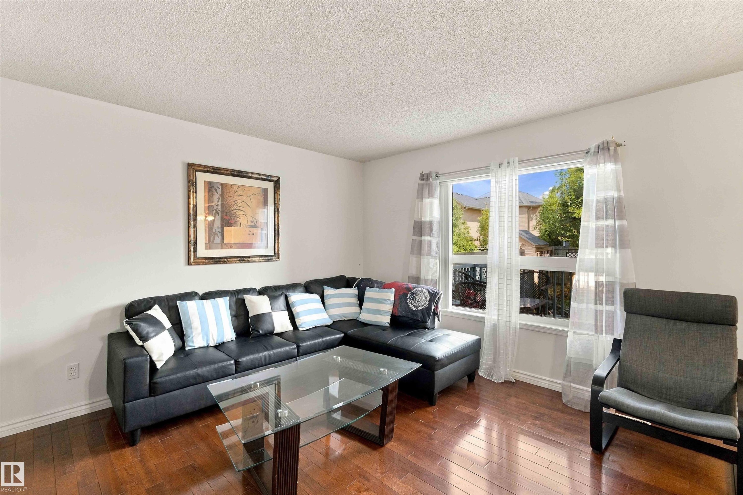 Expansive window with natural light, wood-finish flooring, and neutral wall tones - 3524 Mclean Crescent Sw, Edmonton, AB