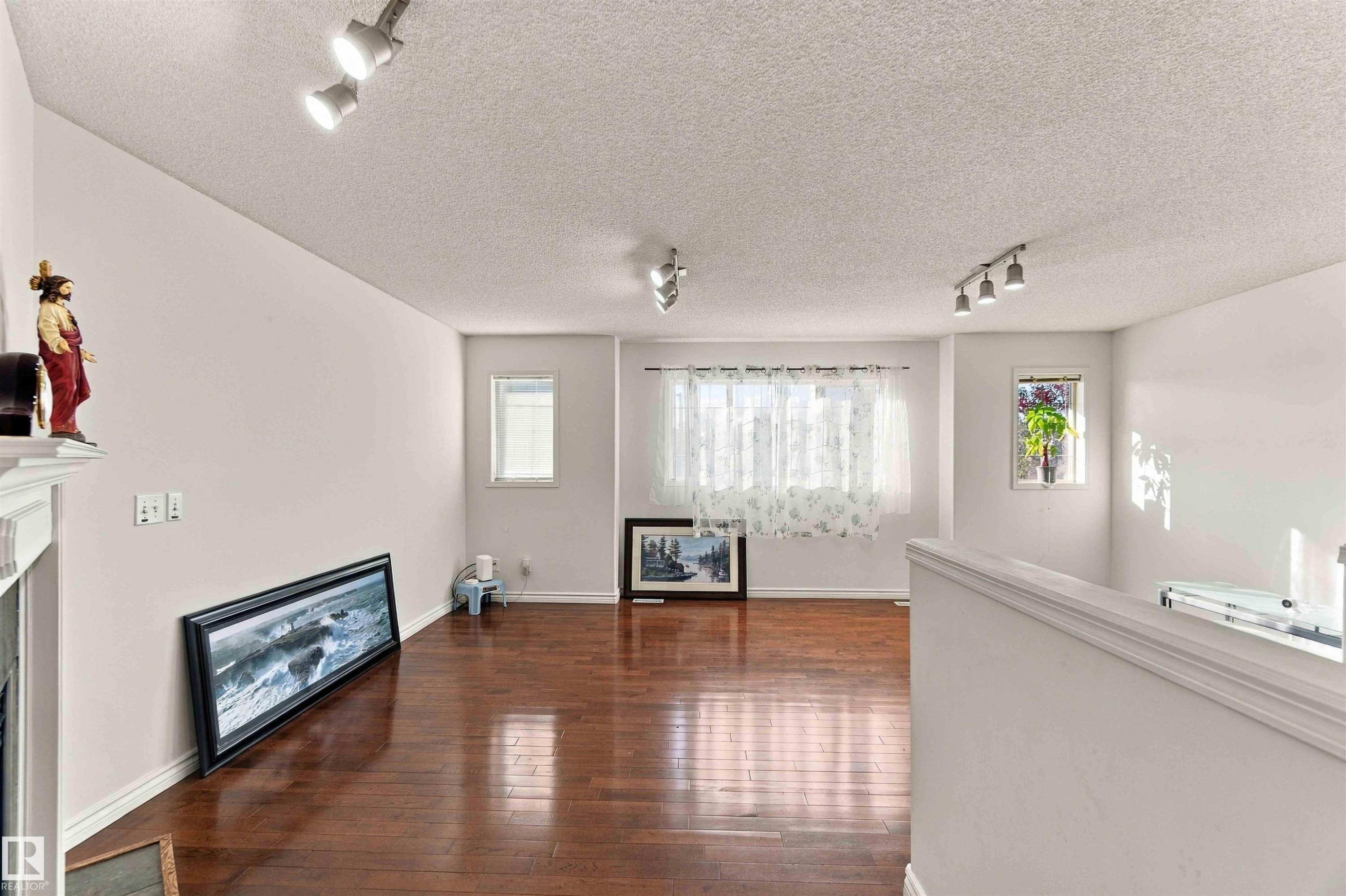 Hardwood-finish flooring, multiple windows providing natural light, white painted walls, and track lighting fixtures - 3524 Mclean Crescent Sw, Edmonton, AB