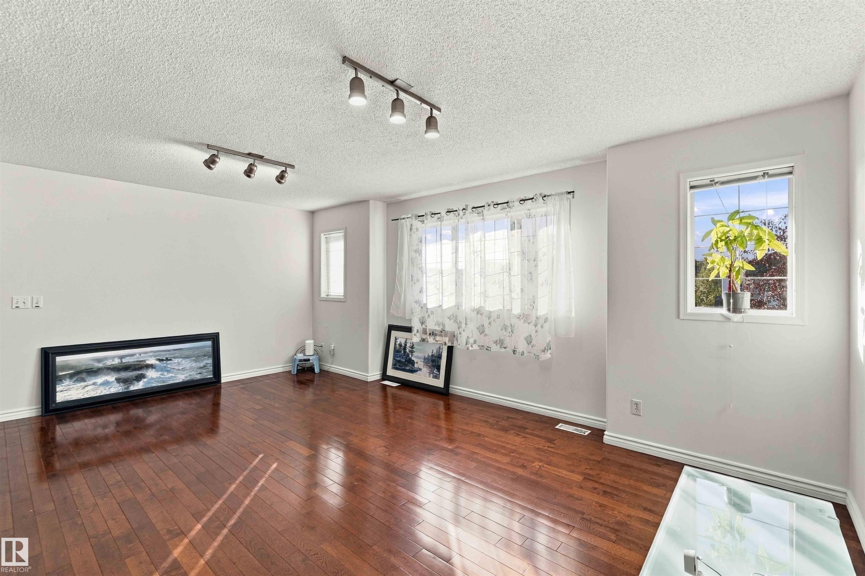 Hardwood flooring, track lighting fixtures, white walls, and multiple windows - 3524 Mclean Crescent Sw, Edmonton, AB