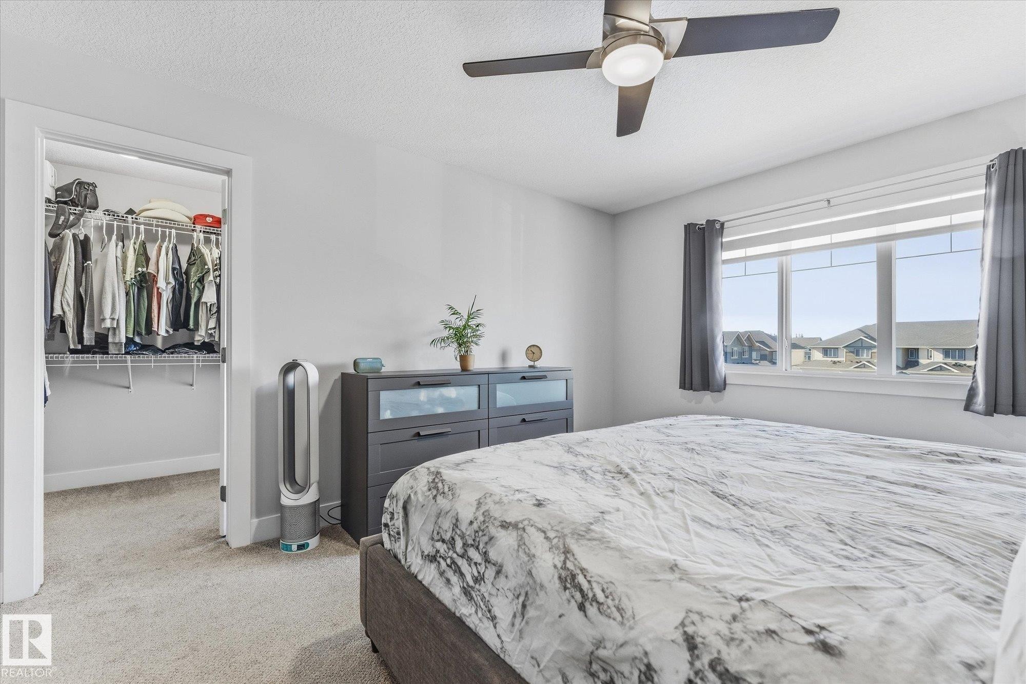 Carpeted room featuring a ceiling fan with integrated lighting, a window with horizontal blinds, and a built-in closet with shelving and hanging rods - #15 4835 Wright Dr Sw, Edmonton, AB
