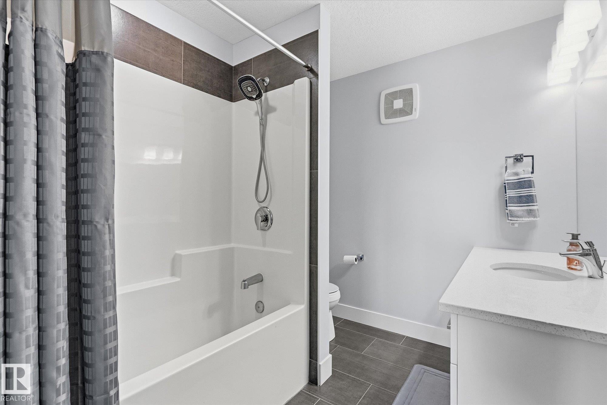 Integrated bathtub and shower with a tile surround, single vanity with an integrated sink, and tile flooring - #15 4835 Wright Dr Sw, Edmonton, AB