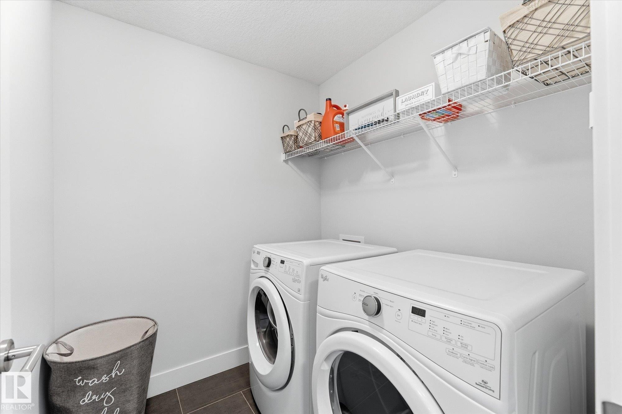 Integrated laundry area featuring dark tile flooring and a white wire shelving unit - #15 4835 Wright Dr Sw, Edmonton, AB