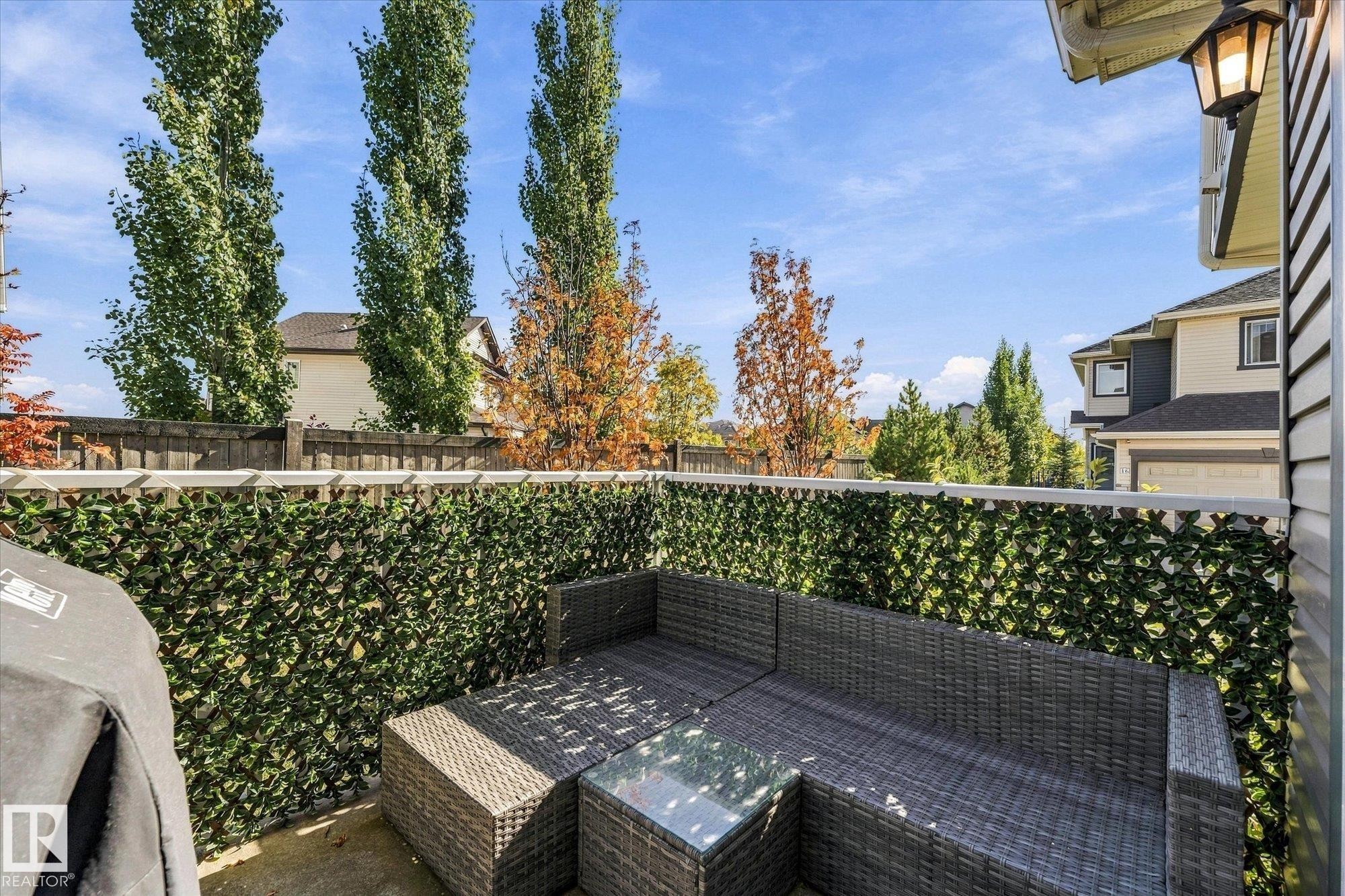 Private outdoor patio space featuring a decorative privacy screen, concrete flooring, and an exterior wall lantern - #15 4835 Wright Dr Sw, Edmonton, AB