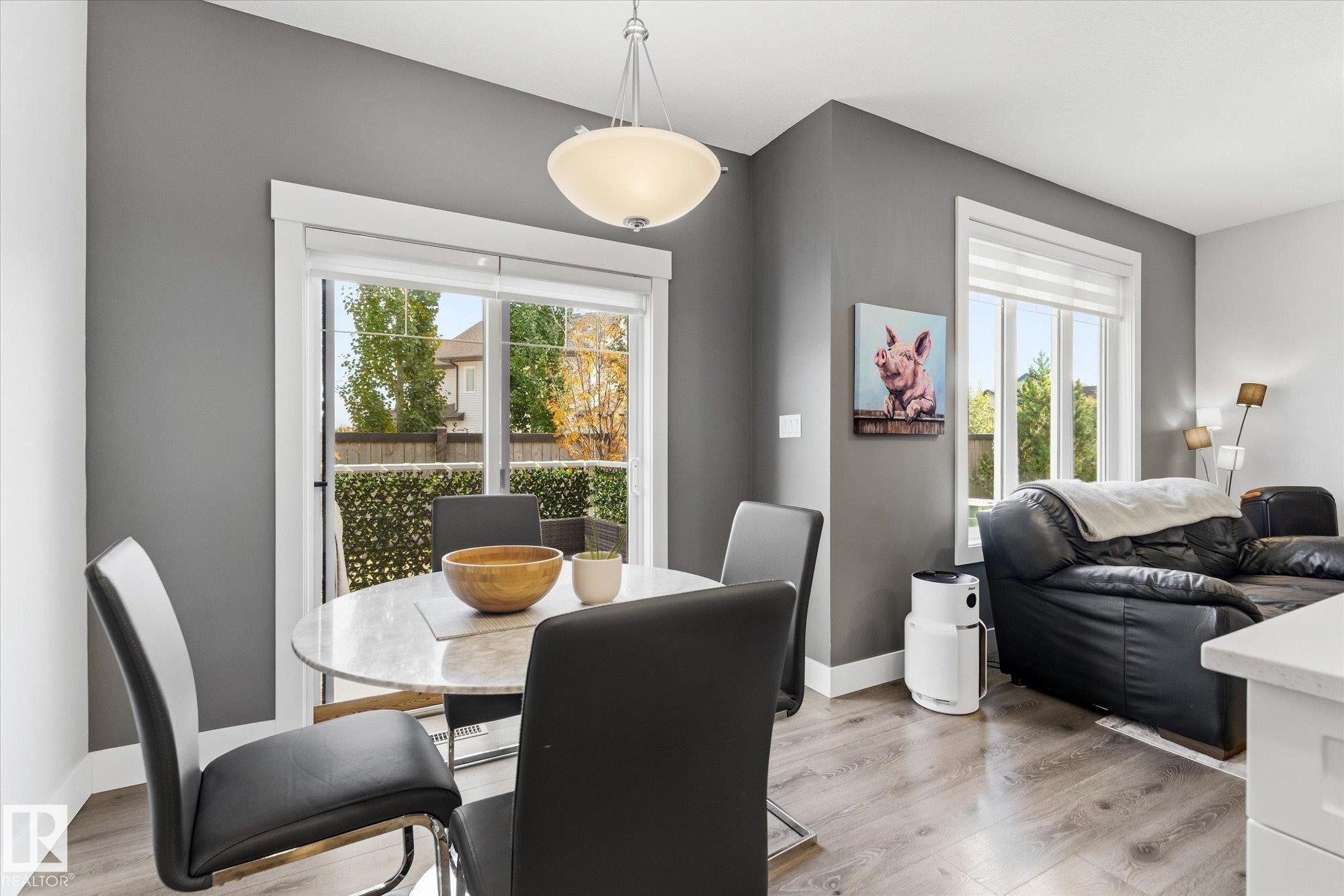 Sliding glass door, pendant light fixture, wood-finish flooring, white trim, and a window with a roller shade - #15 4835 Wright Dr Sw, Edmonton, AB