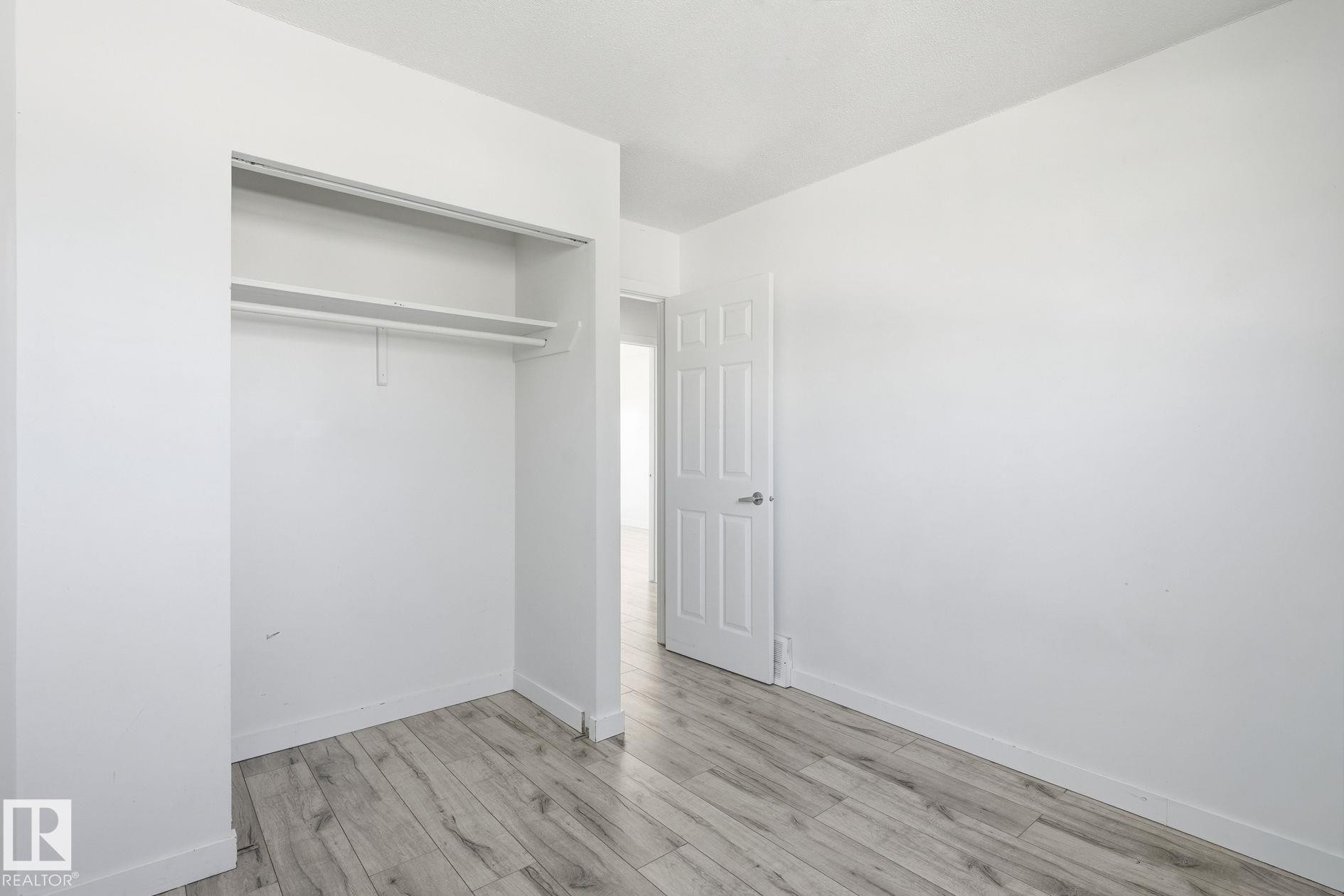 Wood-finish flooring with white walls - 164 Dickinsfield Court Nw, Edmonton, AB