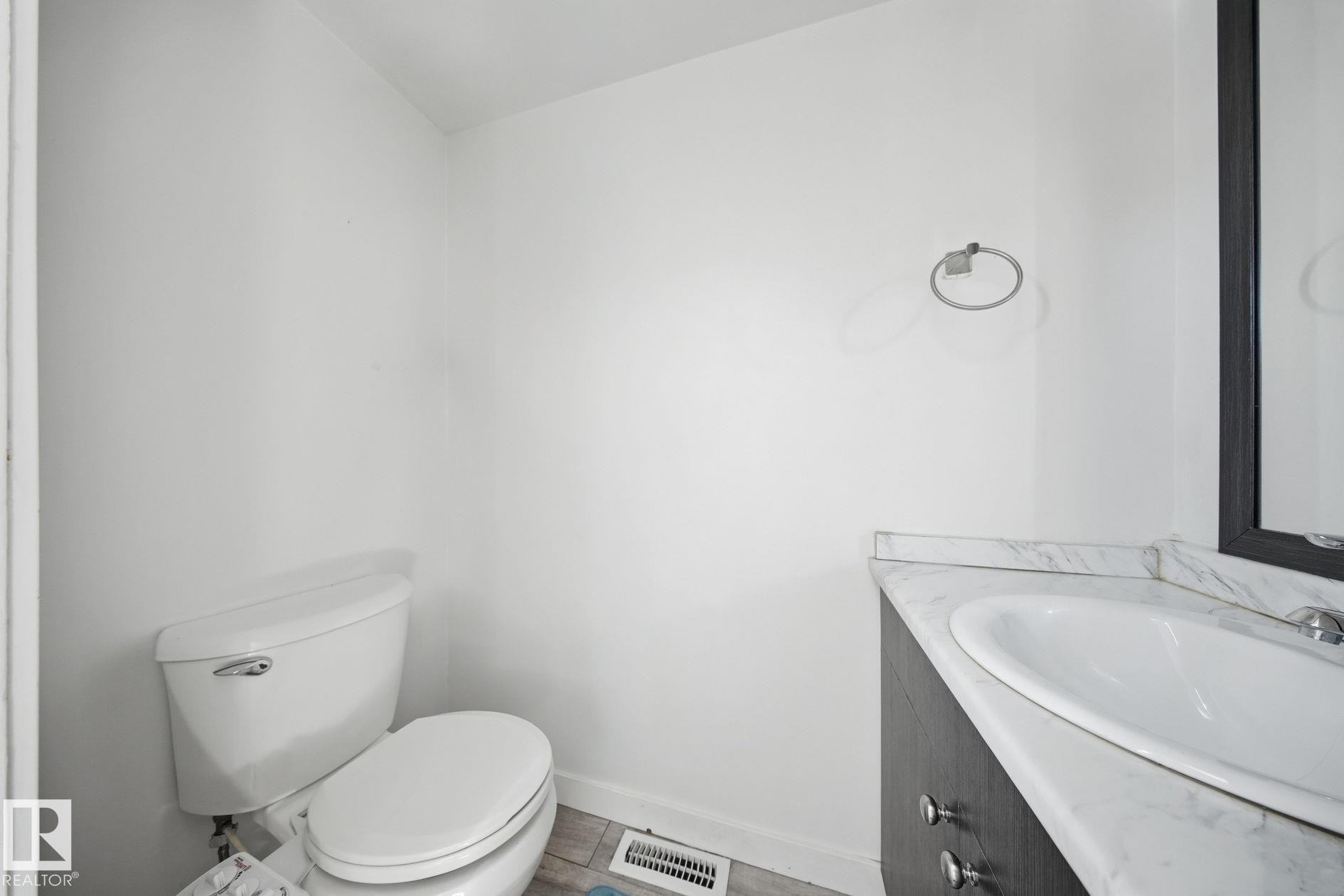 White toilet and a vanity with a white countertop, featuring an undermount sink - 164 Dickinsfield Court Nw, Edmonton, AB