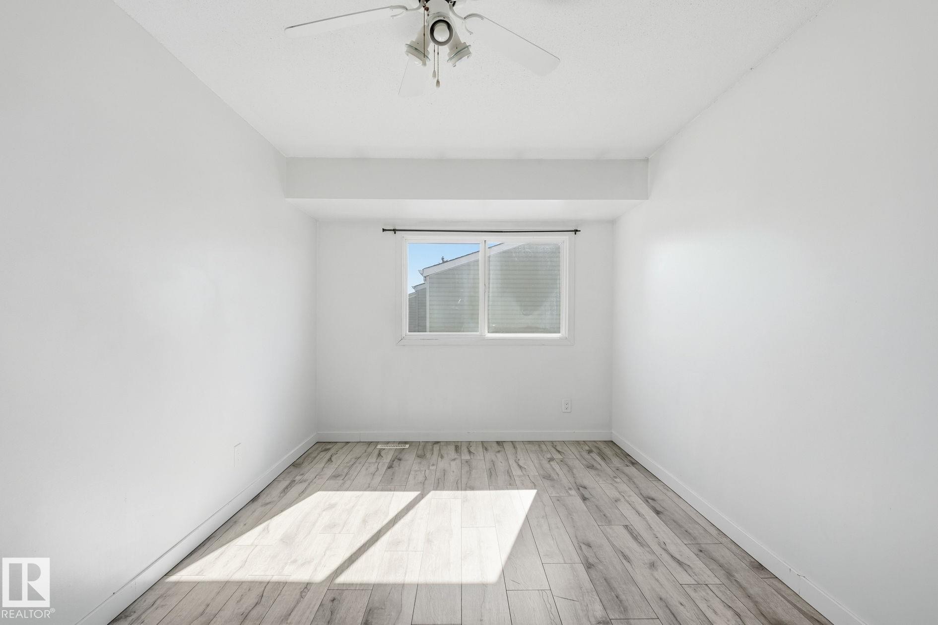 White walls with wood-finish flooring, a ceiling fan, and a window with blinds - 164 Dickinsfield Court Nw, Edmonton, AB